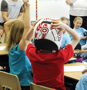 A Grade 2 student tries on a luge helmet during the Classroom Champions discussion on May 6. The design on the back is supposed to be a stylized orca.